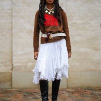 Guest wears a white large pearls with silver pendants necklace, a dark brown with embroidered red pattern pullover, a white latte matte leather belt,...