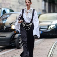 Guest wears a white oversized shirt, black overalls, pearl necklaces, dark brown leather bag, pearl necklaces as belt, black open-toe leather shoes,...
