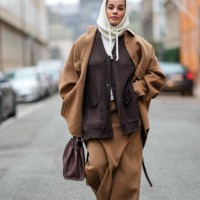 Guest wears a white ribbed wool hood, a brown full look, an oversized jacket , a cardigan, long skirt, a leather bag, outside Lovechild 1979, during...