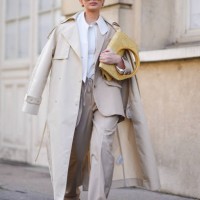 Guest wears a white shirt, a beige trench coat, beige wide-leg pants, orange pointed shoes, a yellow leather bag, sunglasses, outside Giambattista...