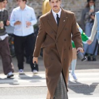 Guest wears a white shirt, a black tie, a dark brown felt wool buttoned long coat, beige checkered print pattern suit pants, black shiny leather...