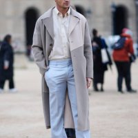 Guest wears a white shirt, a grey and beige trench coat, blue pants, white sneakers, outside Off-White, during the Womenswear Fall/Winter 2024/2025...