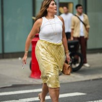 Guest wears a white tank top, a yellow shiny sequined on-knee skirt, beige sandals, outside Proenza Schouler, during New York Fashion Week, on...