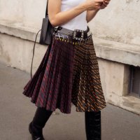 Guest wears a white top, pleated skirt, and long boots outside Prada during the Milan Fashion Week - Womenswear Spring/Summer 2024 on September 21,...