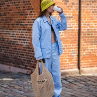 Guest wears a yellow fishnet / mesh bob hat from Prada, a black shoulder-off / cropped top, a pale blue cotton shirt from Prada, matching pale blue...
