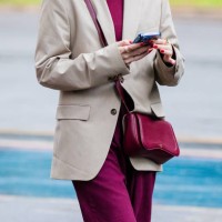 Guest wears beige blazer, burgundy top, matching burgundy pants, burgundy crossbody bag, red nails, gold rings at Sao Paulo Fashion Week 2024 N58 -...