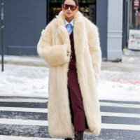Guest wears beige fur coat, burgundy skirt, blouse, suede outside Ulla Johnson during New York Fashion Week on February 09, 2025 in New York City.