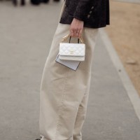 Guest wears beige pants, blakc jacket and white bag outside Chanel during the Womenswear Fall/Winter 2024/2025 as part of Paris Fashion Week on March...