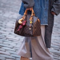 Guest wears beige skirt, brown shoes, denim jacket, grey long scarf and brown Louis Vuitton bag with accessories outside the Gestuz fashion show...