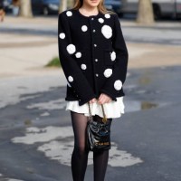Guest wears black cardigan with white flowers decorations, white mini skirt, black tights, black Chanel bag, black Chanel mary jane shoes, outside...