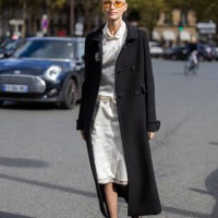 Guest wears black coat, white skirt, blouse outside Miu Miu during Womenswear Spring/Summer 2025 as part of Paris Fashion Week on October 01, 2024 in...