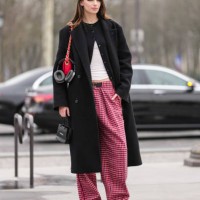 Guest wears black eyeshadow, black cardigan sweater, white top, shiny bright cherry red quilted Chanel leather bag, black double breasted wool coat,...
