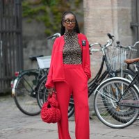 Guest wears black glasses, a brown / beige and black leopard print pattern turtleneck t-shirt, a neon red zipper sport sweater, matching neon red...