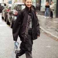 Guest wears black jeans, balck skirt, grey top and black jacket and blue mini bag outside The Cecilie Bahnsen show during Womenswear Spring/Summer...