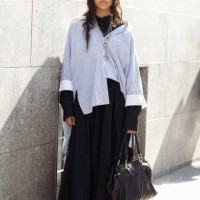 Guest wears black long skirt, black turtle neck, blue and white oversized shirt, statement silver necklaces and sunglasses outside the Avavav fashion...