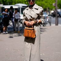 Guest wears black New York Yankee pillbox hat with sheer mesh covering, black sunglasses, white black pattern silk head scarf, pearl necklace, light...