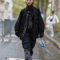 Guest wears black oversized jacket, dark gray t-shirt, black pattern crinkled midi skirt, black loose pants, bright blue leather bag, outside Cecilie...