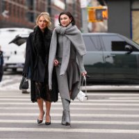 Guest wears black oversized Michael Kors coat, black faux fur scarf, black sheer mesh floral lace midi Michael Kors skirt, shiny black Michael Kors...