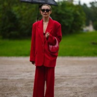 Guest wears black sunglasses, a black bra underwear, a neon red blazer jacket, neon red wide legs pants, a red shiny varnished leather handbag, black...