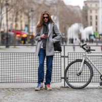 Guest wears black sunglasses, a grey scarf, a grey blazer jacket, dark blue pants, white and grey Nike sneakers shoes, outside Hed Mayner, during the...