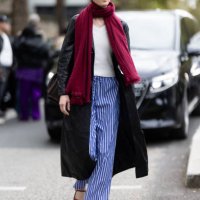 Guest wears black sunglasses, a red scarf, a white sweater, a brown leather trench, blue and white striped trousers and red leather maryjane shoes...