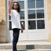 Guest wears black sunglasses, a white t-shirt, navy blue suit pants, white leather laces sneakers , outside Dior , during the Haute Couture...