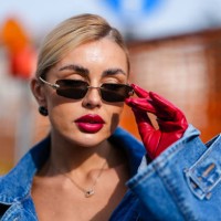 Guest wears black sunglasses, black earrings, silver necklace, red leather gloves, outside Diesel, during the Milan Fashion week Women's Fall/Winter...