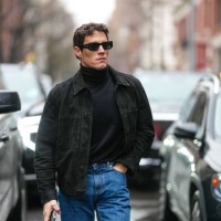Guest wears black sunglasses, black turtleneck long sleeve shirt, black cropped jacket, navy blue straight fit denim jean pants, outside Todd Snyder,...
