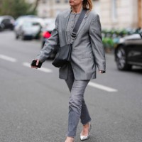 Guest wears black sunglasses, dark gray buttoned cardigan sweater, dark gray oversized blazer jacket, shiny black leather bag, dark gray denim jean...