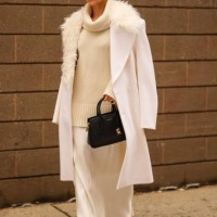 Guest wears black sunglasses, gold earrings, cream knit high neck oversized sweater, white oversized double breasted Michael Kors blazer coat with...