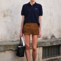 Guest wears black sunglasses, gold hoop earrings, black three buttoned short sleeve cotton shirt, brown suede mini skirt, silver rings, black small...