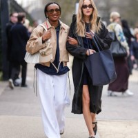 Guest wears black sunglasses, gold pearl earrings, dark green shirt, navy blue jacket, light brown cropped Lacoste coat, white Lacoste leather bag,...