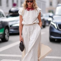 Guest wears black sunglasses, red necklace, white puffy short sleeve shirt, white maxi skirt with slit, black leather Bottega Veneta bag, black sheer...
