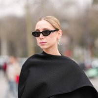 Guest wears black sunglasses, silver hoop earrings, black cape, outside Chanel, during the Paris Fashion week Women's Fall/Winter 2025-2026 on March...