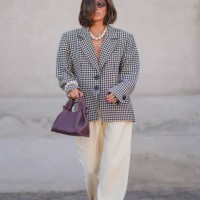 Guest wears black sunglasses, silver necklace, white beaded necklace, black and white pattern oversized blazer jacket, silver rings, white pearl...