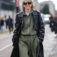 Guest wears black sunglasses, white t-shirt, dark olive green zipped bomber jacket, dark olive green loose trouser pants, shiny black leather trench...