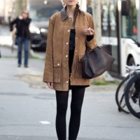 Guest wears black tights, brown suede jacket, dark brown bag and suede flats outside the Christopher Esber fashion show during the Womenswear...