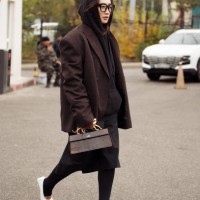 Guest wears black tights, white pointy shoes, brown bag with golden details, black hoodie and brown oversized blazer and black skirt during the 10th...