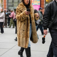 Guest wears black turtleneck long sleeve shirt, light blue denim jean pants, light brown cheetah animal pattern/print faux fur coat, shiny black...