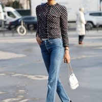Guest wears black white and red striped jacket, blue jeans, white Chanel bag, outside Chanel, during the Womenswear Fall/Winter 2025/2026 as part of...