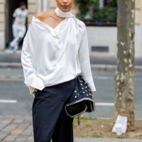 Guest wears black white bag, pants, white blouse outside Stella McCartney during Womenswear Spring/Summer 2025 as part of Paris Fashion Week on...