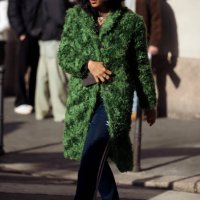 Guest wears blue Adidas pants, a green fur coat, and white ballet shoes with crystal decorations outside Ferrari during the Milan Fashion Week -...