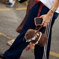 Guest wears blue adidas pants, Marlboro red and white shirt and brown Miu Miu bag with accessories outside the vision show during day two of the...