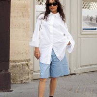 Guest wears blue bermuda shorts, a white shirt, black socks, black shoes, and sunglasses outside Patou during the Haute Couture Fall/Winter 2024/2025...
