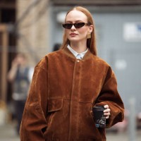 Guest wears blue jeans, brown suede jacket and black bag outside the Herskind fashion show during the Copenhagen Fashion Week Autumn/Winter 2025 on...