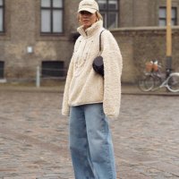 Guest wears blue jeans, fur jumper, pearl necklace, beige cap, and Loewe black bag outside Rolf Ekroth during the Copenhagen Fashion Week AW24 on...