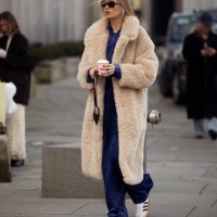 Guest wears blue pants, a blue shirt, and a beige teddy bear coat outside TG Botanical during Copenhagen Fashion Week AW24 on February 1, 2024 in...