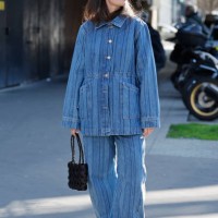 Guest wears blue striped denim jacket with matching jeans, red heels, black bag, outside Stella McCartney, during the Womenswear Fall/Winter...