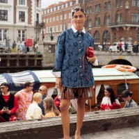 Guest wears brown mini skirt, blue denim shirt, red bag and green flats VIP guest trip with a boat to the Marimekko show during day four of the...