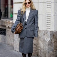 Guest wears brown Miu Miu bag, grey suit outside Magda Butrym presentation during the Womenswear Fall/Winter 2025/2026 as part of Paris Fashion Week...